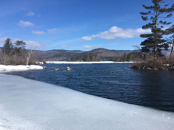 The hills surrounding partially frozen Squam Lake - April